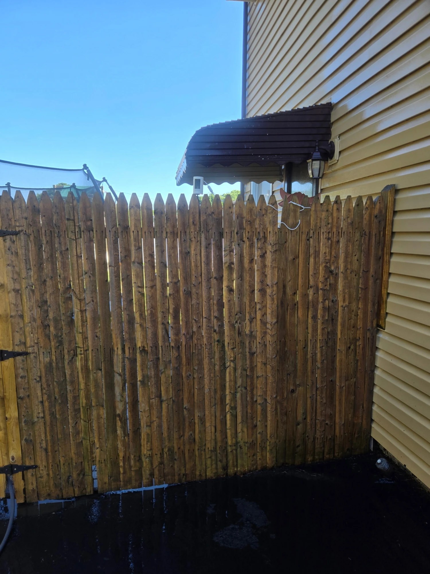 Wooden fence after pressure washing looking cleaner and brighter